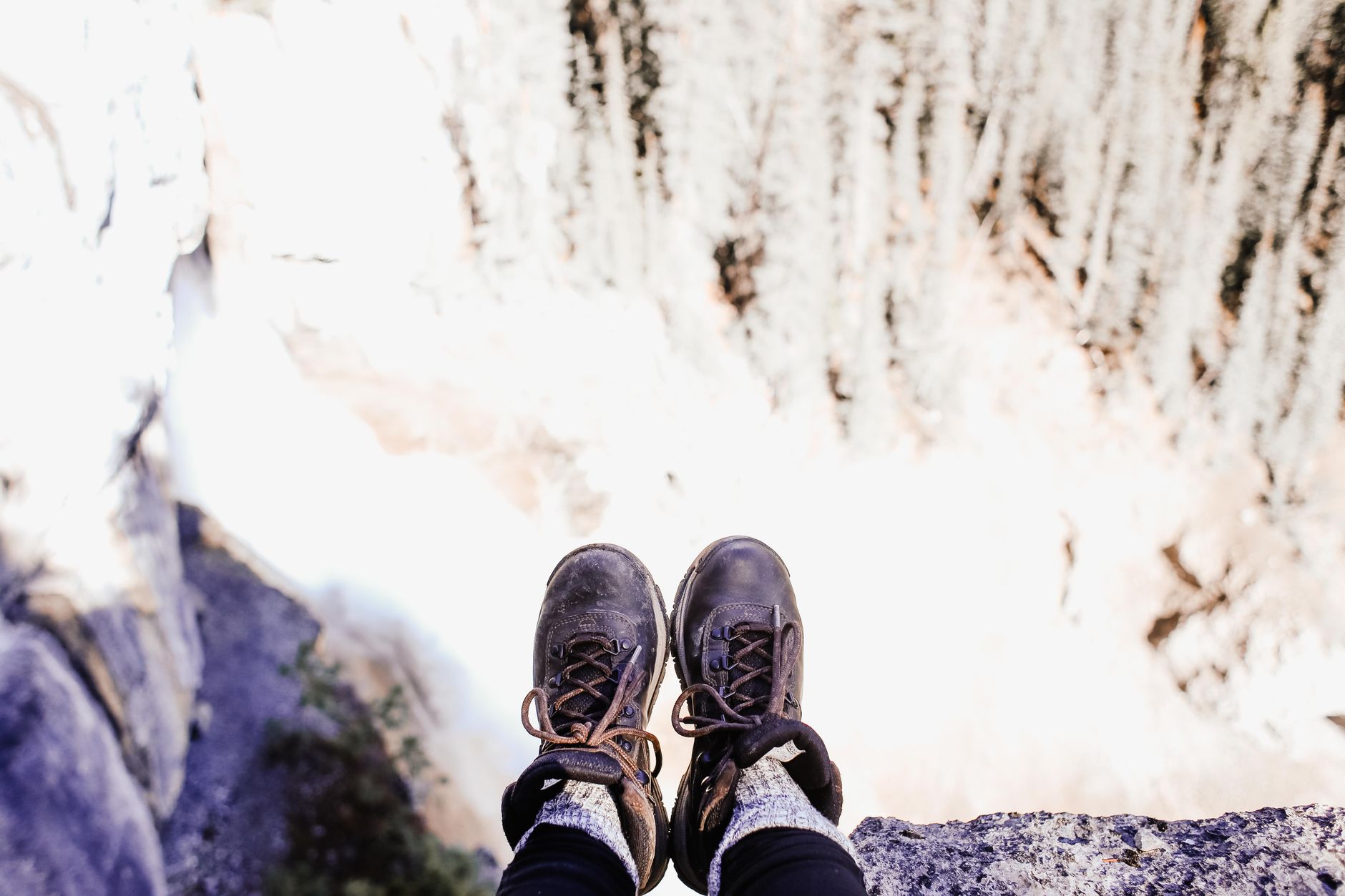 Buty trekkingowe nad krawędzią urwiska w Alpach, widok w dół