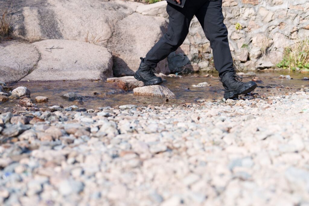 Turysta w sprzęcie trekkingowym przekracza kamienisty strumień